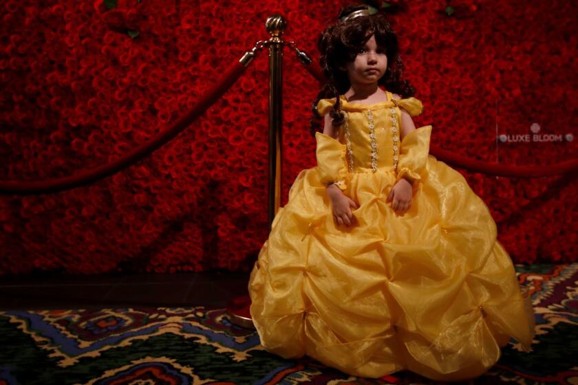 Olivia Bustillos, 3, of El Monte poses in front of a wall of roses in the lobby of Hollywood's El Capitan Theatre during the first public screening of "Beauty and the Beast" on March 16.