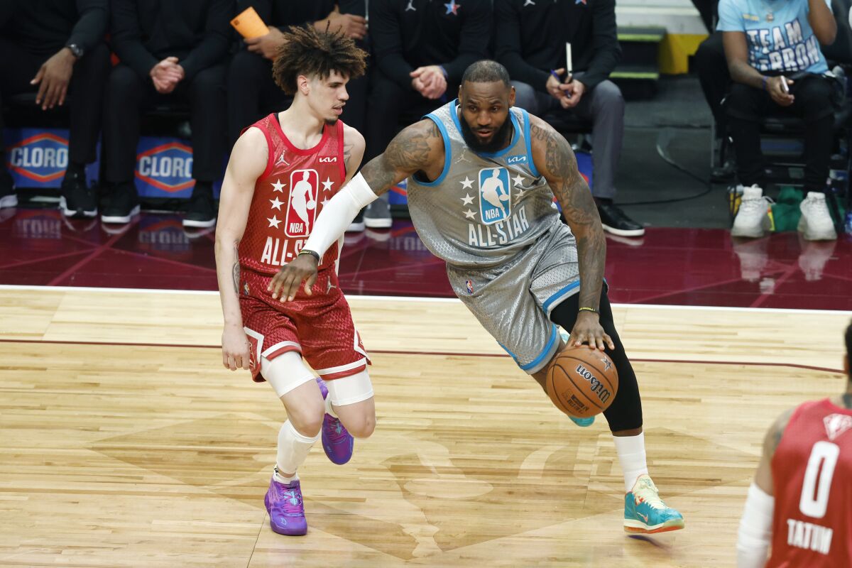 A man, right, dribbles a basketball past another man