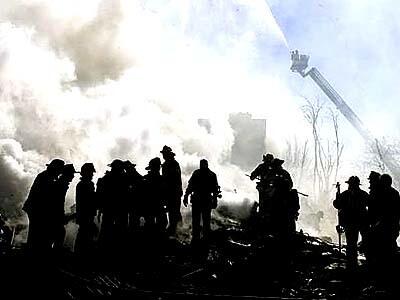 Firefighters work amid the debris from the jetliner crash at Beach 131st Street and Newport Avenue in Belle Harbor, on the Rockaway Peninsula of Queens.