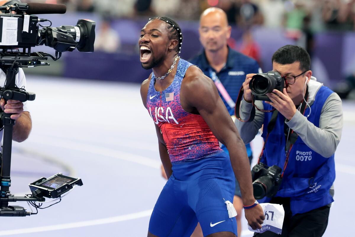 American Noah Lyles shouts toward TV cameras and celebrates his gold medal after winning the 100-meter final