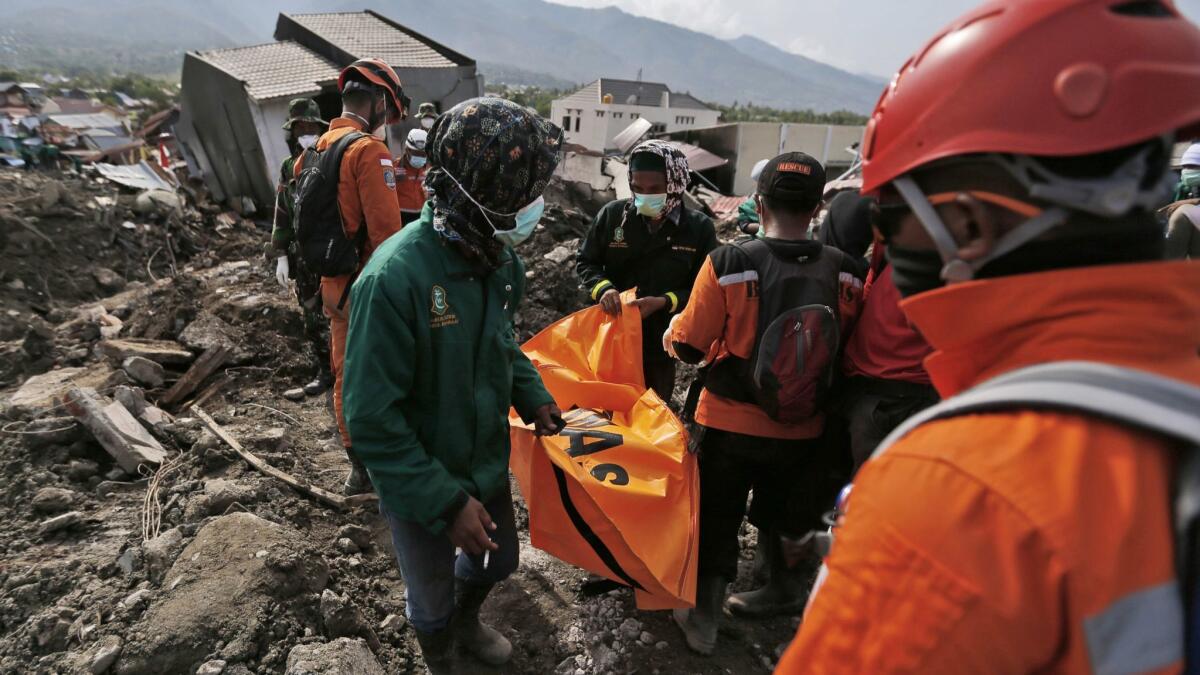 Workers carry a body bag containing the remains of an earthquake victim recovered from under rubble in the city of Palu on the Indonesian island of Suwalesi on Thursday.
