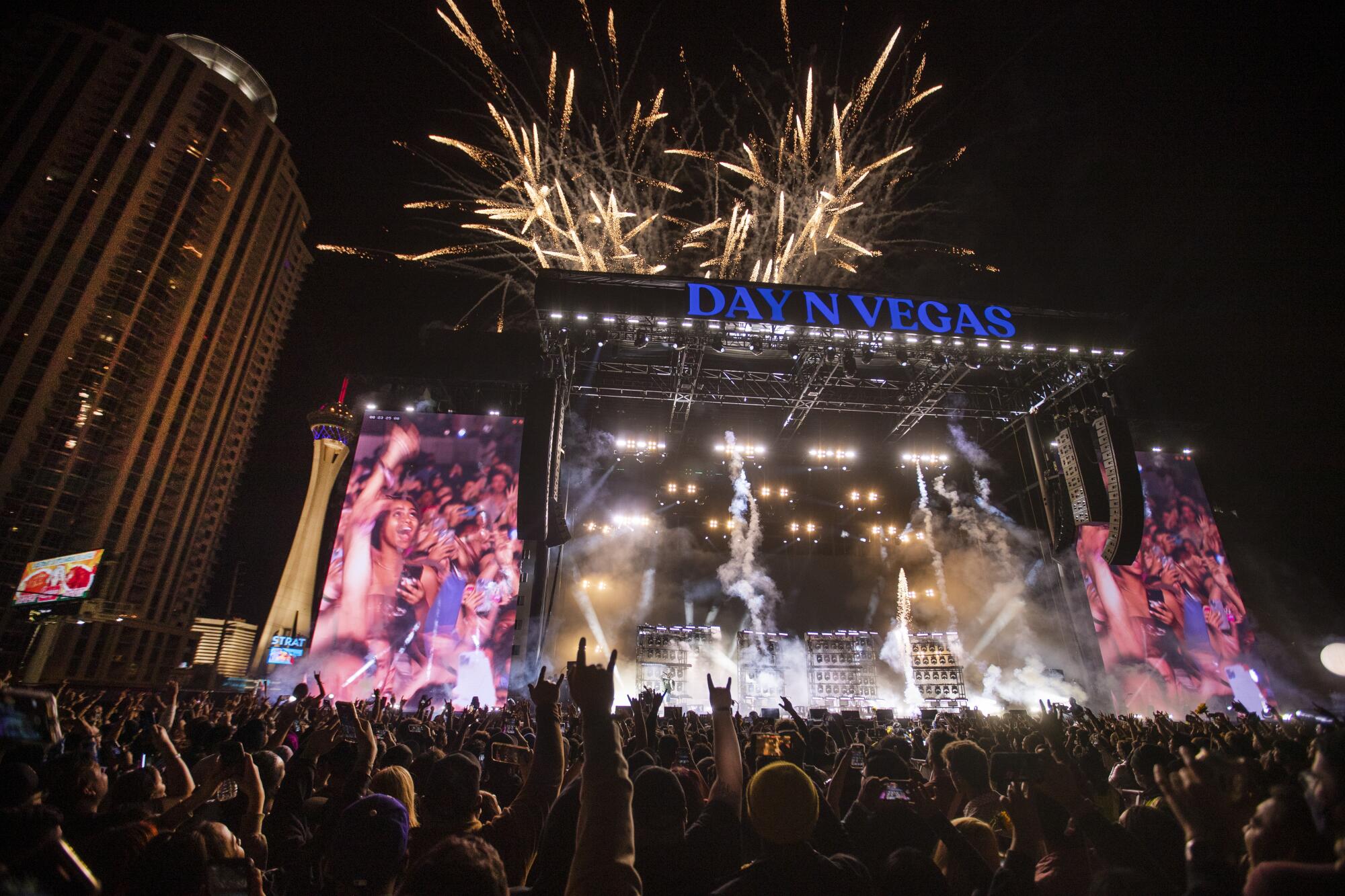 Fireworks explode behind a stage with a giant "Day N Night Vegas" sign