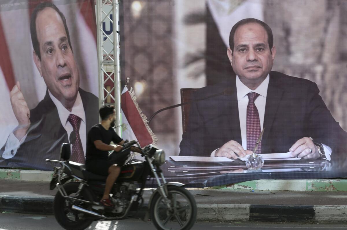 A motorcyclist passes large posters of Egyptian President Abdel Fattah Sisi displayed in Gaza City.