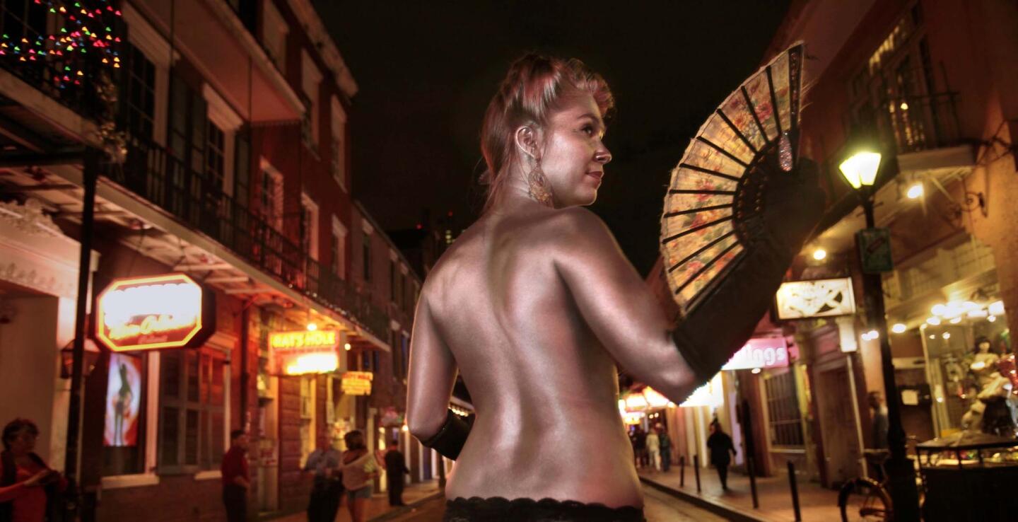 Performer Holly Hawthorne sports a coat of silver paint on Bourbon Street, which is best explored after the sun goes down. In daylight, the street in the French Quarter can just look tawdry.