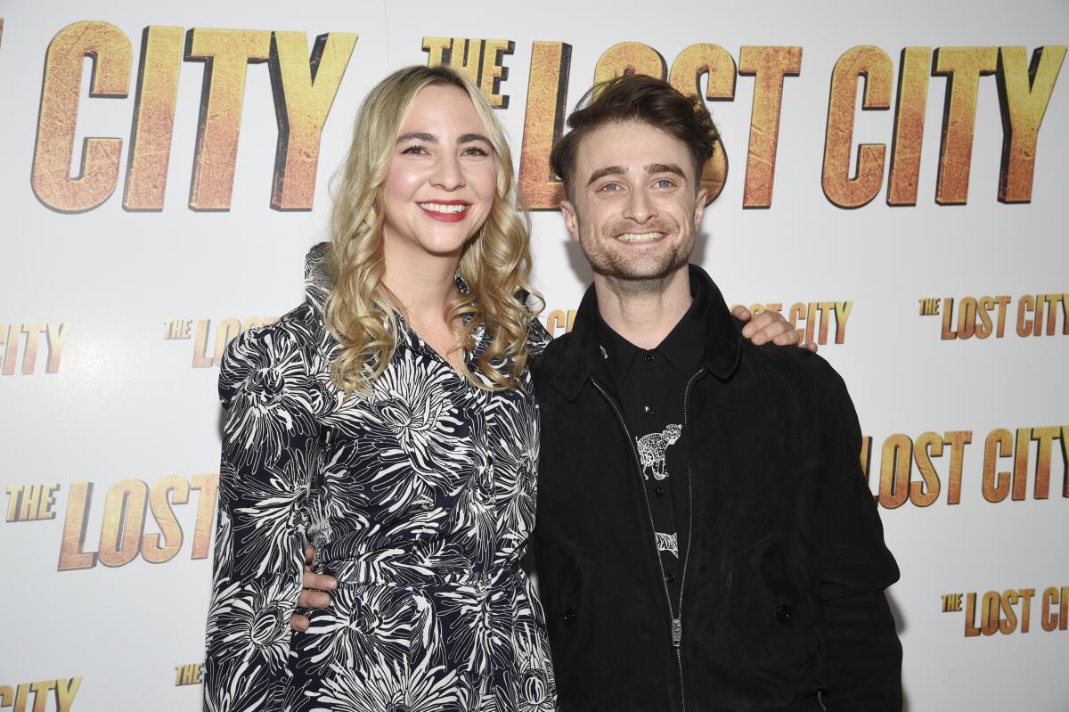 Erin Darke and Daniel Radcliffe stand next to each other and smile on a red carpet