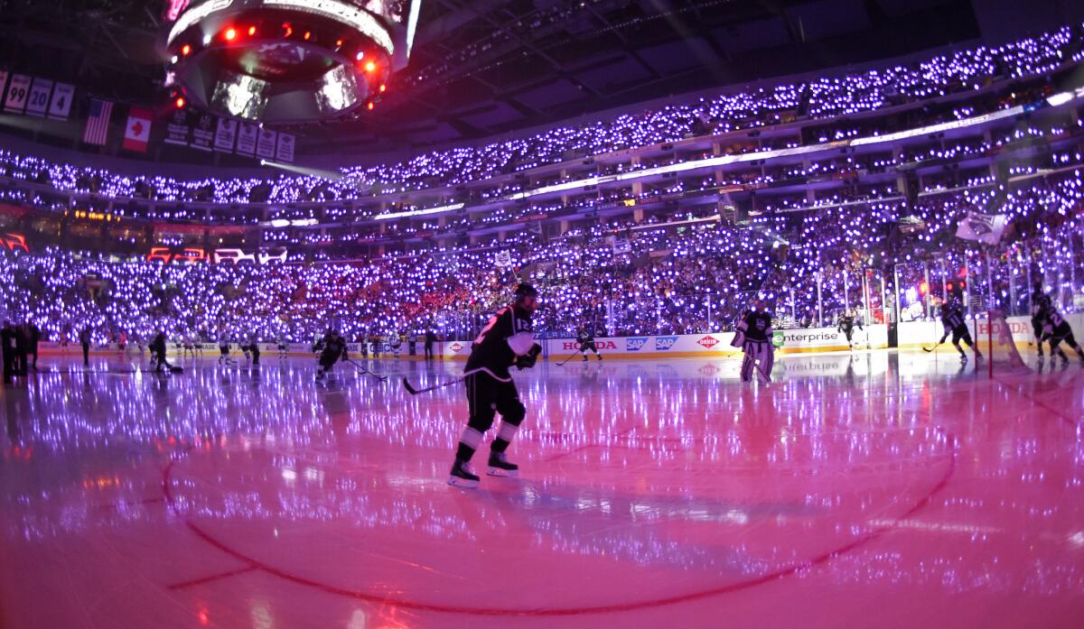 Members of the L.A. Kings skate around the ice as fans in the stands wave purple glow sticks in honor of Prince before the Kings' NHL playoff game against San Jose on Friday night at Staples Center.