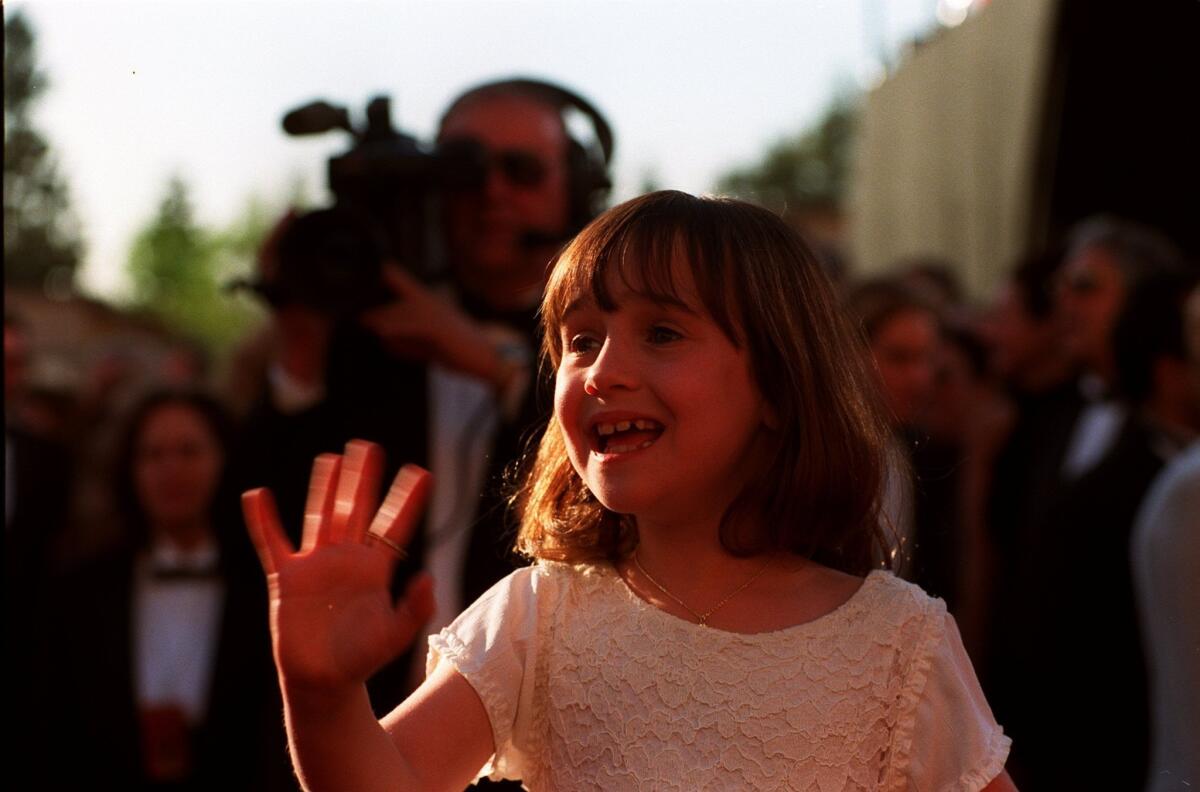 A young Mara Wilson waves to fans at a Hollywood event.