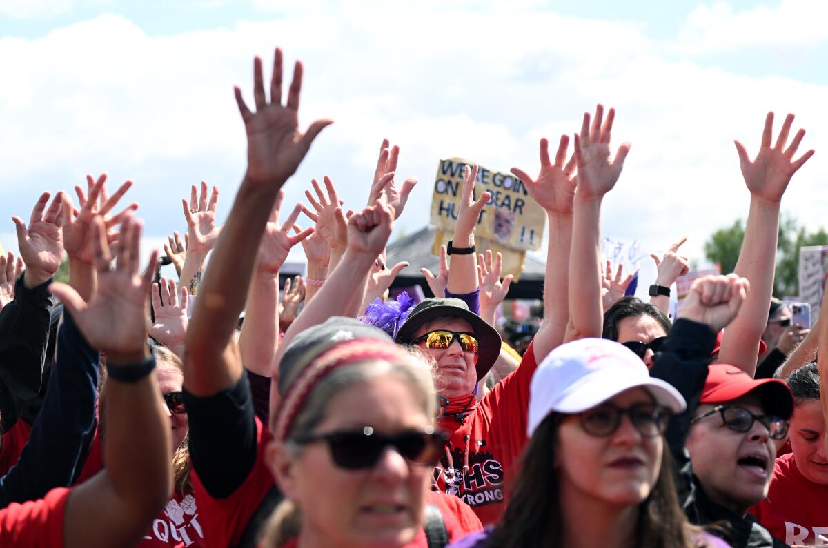 Los Angeles school workers raise their hands at a rally.