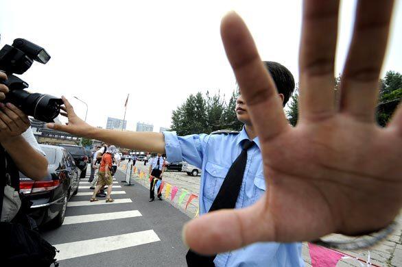 In Beijing, a policeman discourages photographers from taking pictures as they cordon off the park where they had detained pro-Tibet demonstrators near the main Olympic stadium on Wednesday.