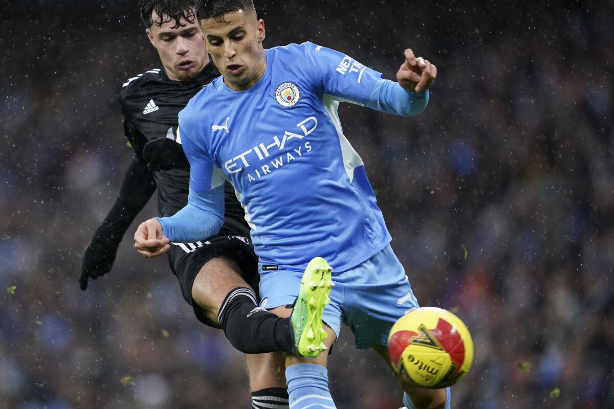 Fulham's Neco Williams fights for the ball with Manchester City's Joao Cancelo, right, during an English FA Cup fourth round soccer match between Manchester City and Fulham at the Etihad Stadium in Manchester, England, Saturday, Feb. 5, 2022. (AP Photo/Jon Super)