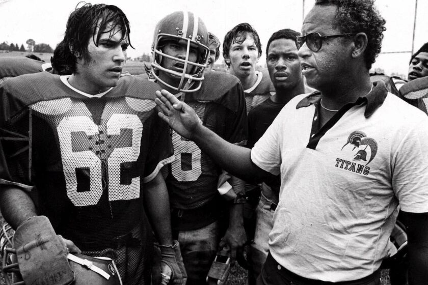 File= This 1971 file photo shows Alexandria, Va's., T.C. Williams High School football coach Herman Boone, right, during a break at summer camp, with guard Johnny Colantuoni, (62) and John Vaughn, center. Boone, the Virginia high school football coach who inspired the movie “Remember the Titans,” has died. He was 84. Boone guided T.C. Williams High School to a state championship while navigating the early days of desegregation. Aly Khan Johnson, an assistant coach for Boone beginning in 1972, said the coach died Wednesday, Dec. 18, 2019, at his home In Alexandria, Va. Johnson said a funeral home operated by his wife is handling the arrangements, which are not complete. (AP Photo/File)
