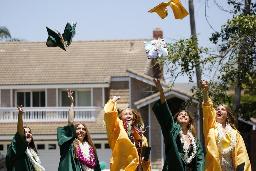 A group of graduates toss their caps into the air for a photo after receiving their diploma from Edison High School, during a drive-thru graduation ceremony at the school in Huntington Beach on Thursday, June 11, 2020.