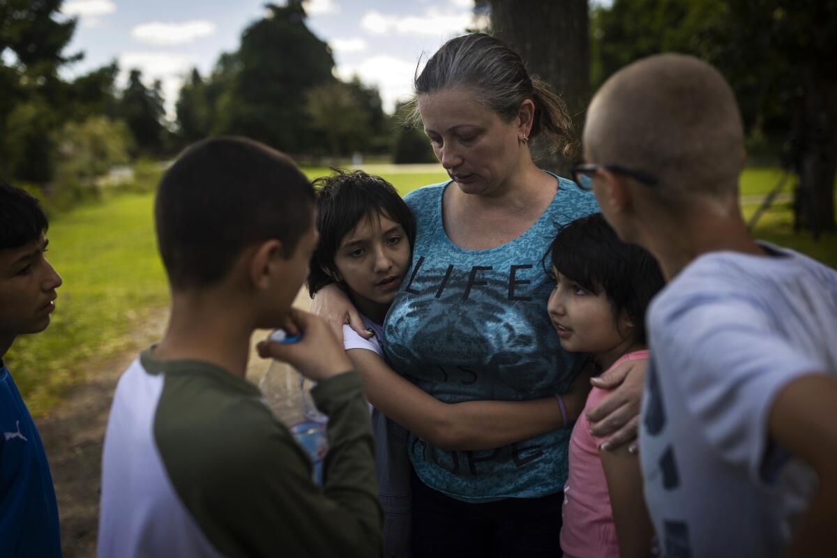 Olga Lopatkina embraces her adopted children in a park in Loue, western France, Saturday, July 2, 2022. After two months of negotiation and an initial objection from a senior Russian official, DPR authorities finally agreed to allow a volunteer with power of attorney from Lopatkina to collect her children who were evacuated from Mariupol. An Associated Press investigation has found that Russia’s strategy to take Ukrainian orphans and bring them up as Russian is well underway. (AP Photo/Jeremias Gonzalez)