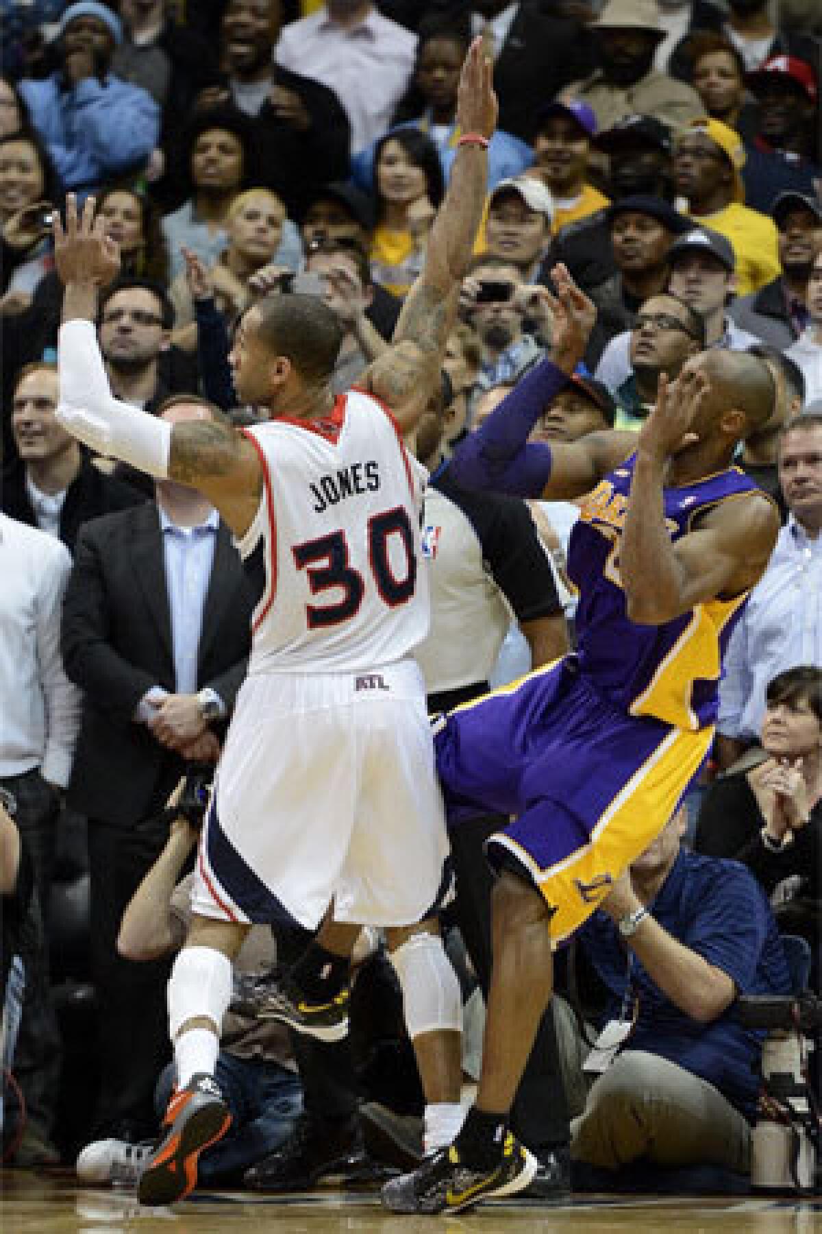 Kobe Bryant comes down on his left ankle after taking a closing-seconds shot against Atlanta Hawks forward Dahntay Jones.