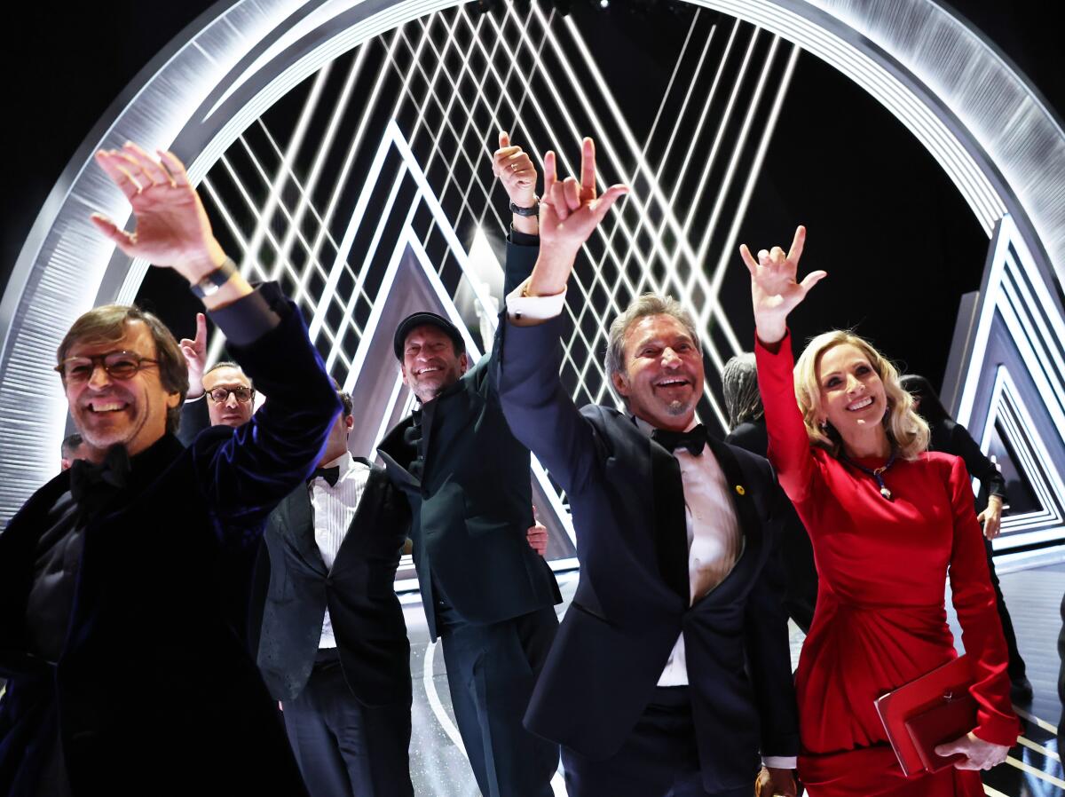 Marlee Matlin, Troy Kotsur and other "CODA" cast members with producers wave at the 2022 Oscars.
