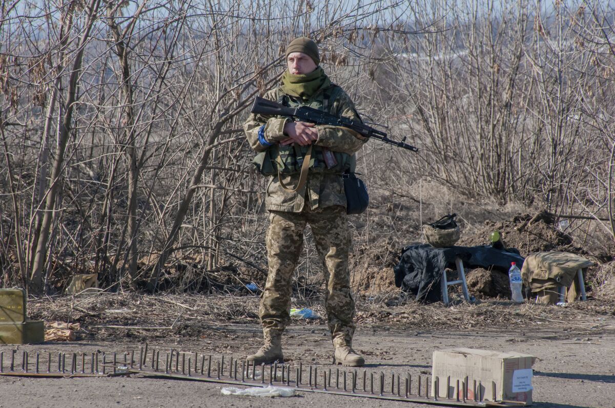 A Ukrainian soldier stands outside with a gun.