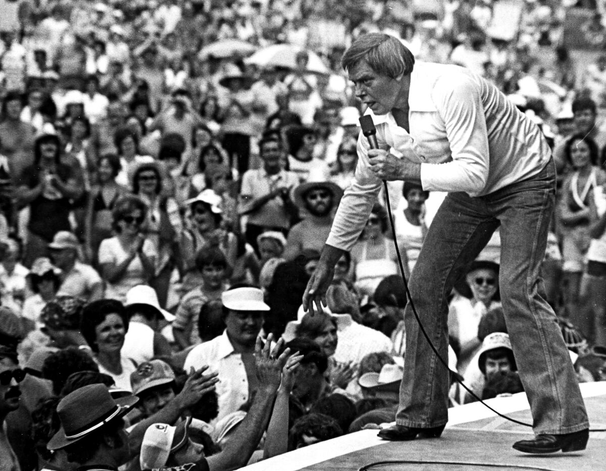 Tom T. Hall performing on stage to a large crowd in 1977.