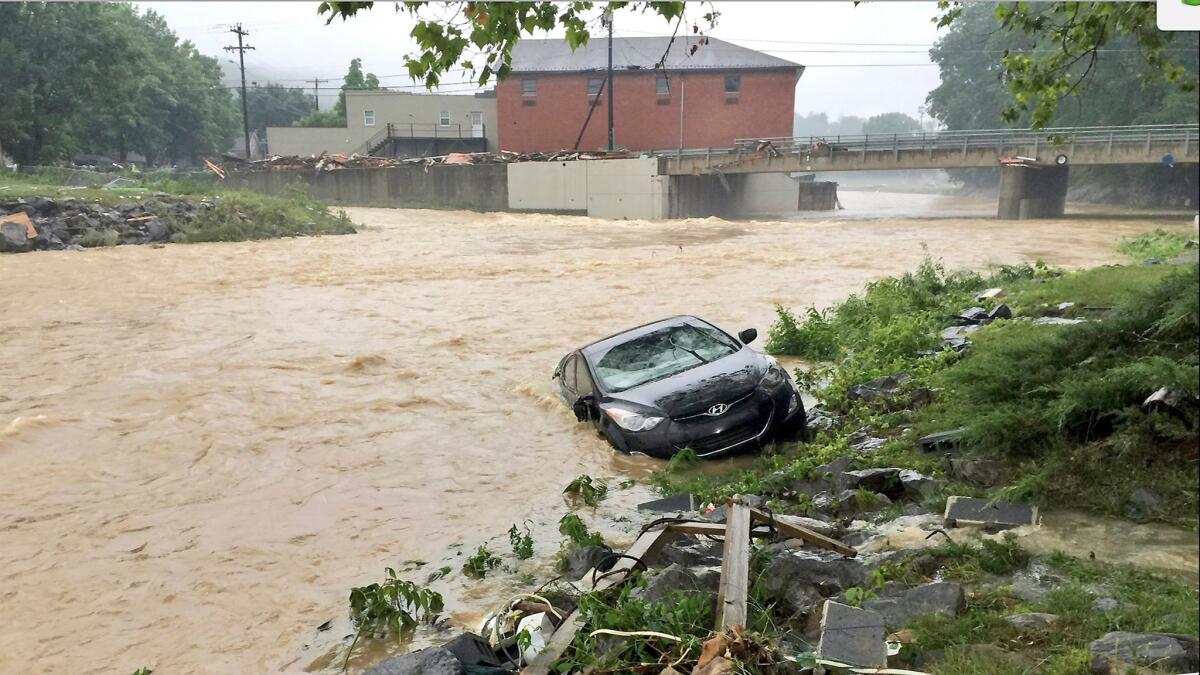 A vehicle is partially submerged in a stream after a heavy rain near White Sulphur Springs, W.Va., on June 24.