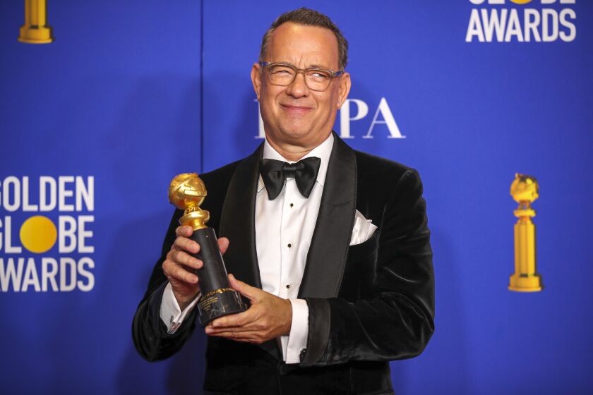 Tom Hanks smiling and holding a Golden Globe trophy