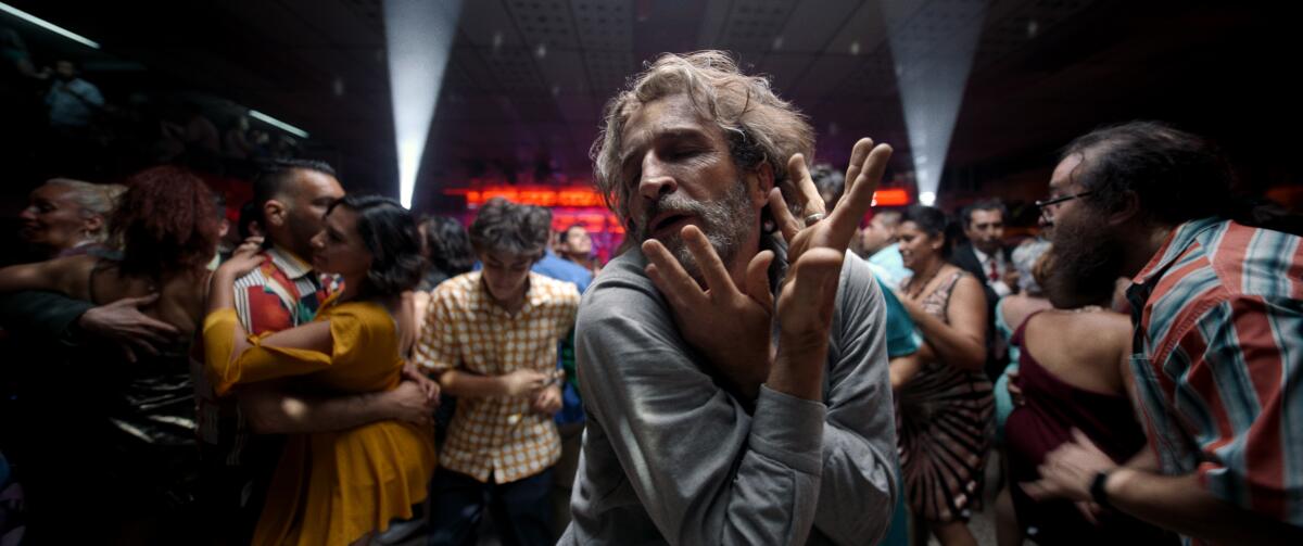 A man with graying hair and a beard dances in crowd in the movie "Bardo, False Chronicle of a Handful of Truths."