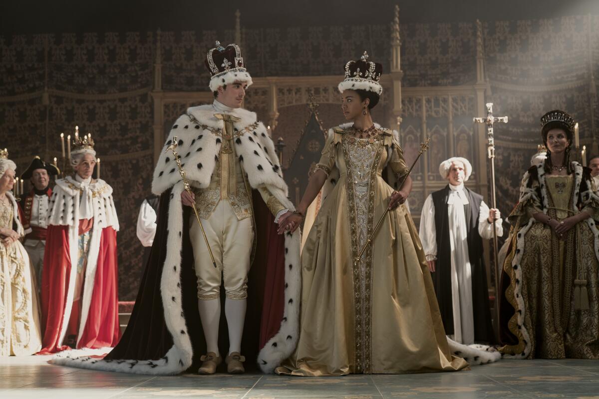 King George and Queen Charlotte in gilded clothing look at one another.