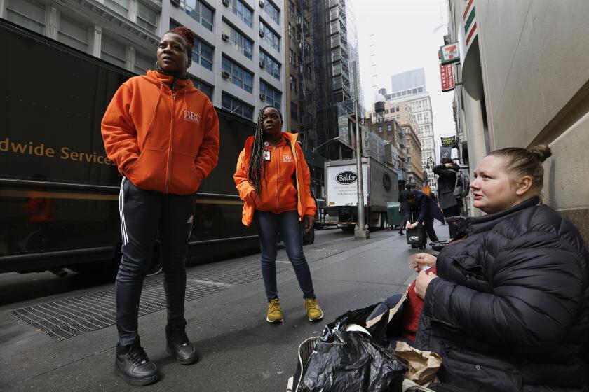 NEW YORK, NEW YORK--APRIL 14, 2018--Yvonne Boynes, left, and Aisha Martin, right, do street outreach for BRC (Bowery Residents' Committee) in the financial district of Manhattan, New York. They talk to Laura Miller, age 36, right, who panhandles on Nassau Street. Miller says she can sometimes make $100 per day, and will get a hotel room for two nights with the money. The goal of the outreach is to get the homeless into the shelter system, but many don't want to go, saying they feel the shelters are unsafe. Under the laws of New York, homeless have a right to shelter and many agencies work to provide that. (Carolyn Cole/Los Angeles Times)