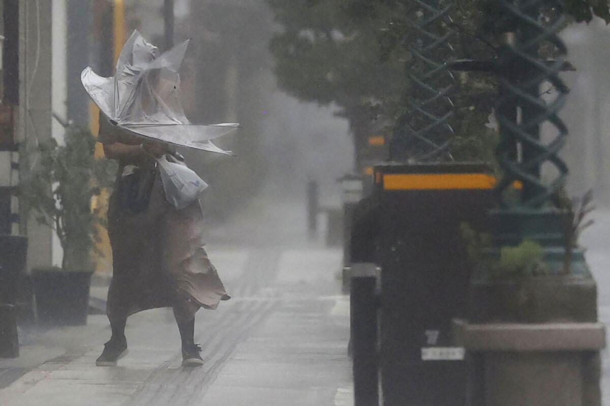 A woman makes her way through the strong wind and rain.