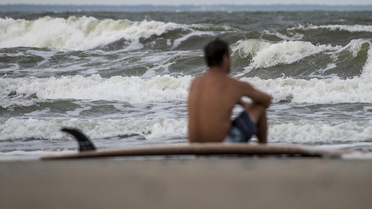 Eric Dunn sit on the northern end of Tybee Island's beach watching larger than average waves roll in as a result of approaching Hurricane Matthew, Tuesday, Oct. 4, 2016 in Tybee Island, Ga.