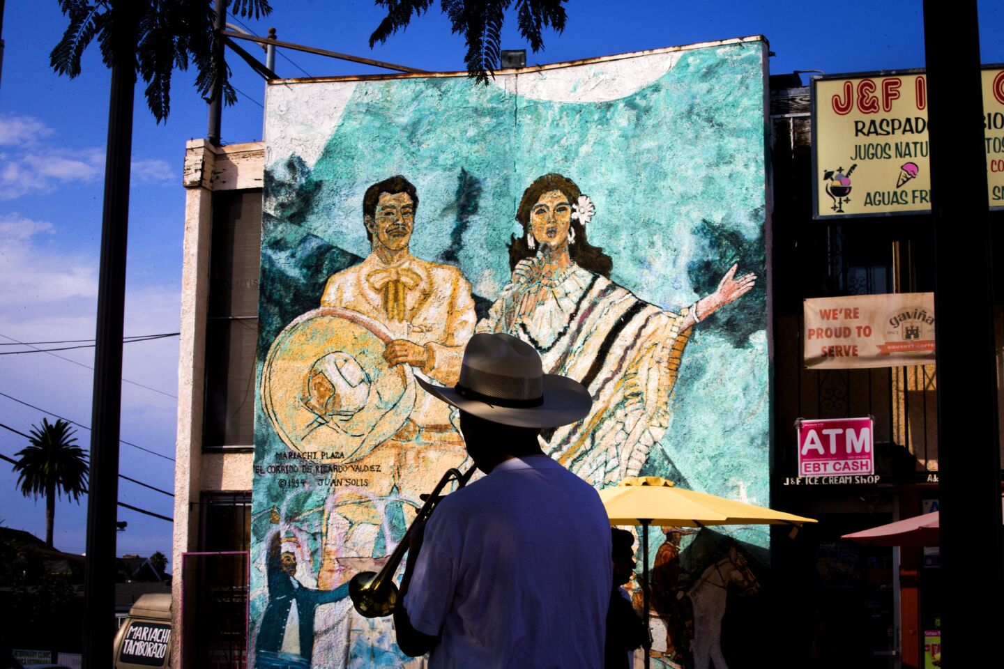 Mariachi player Natolio Nuñez, who has been playing trumpet for 40 years, practices in the shade while silhouetted against a mural amid a heat wave where temperature reached 93 degrees at Mariachi Plaza de Los Angeles in Boyle Heights.