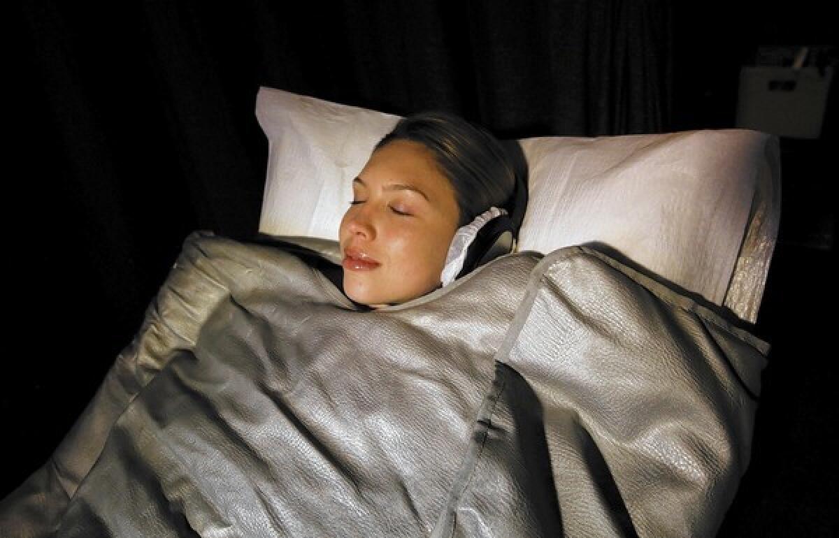 Erica Eynon, who works at Shape House, takes a sweat treatment using a heated sleeping bag.