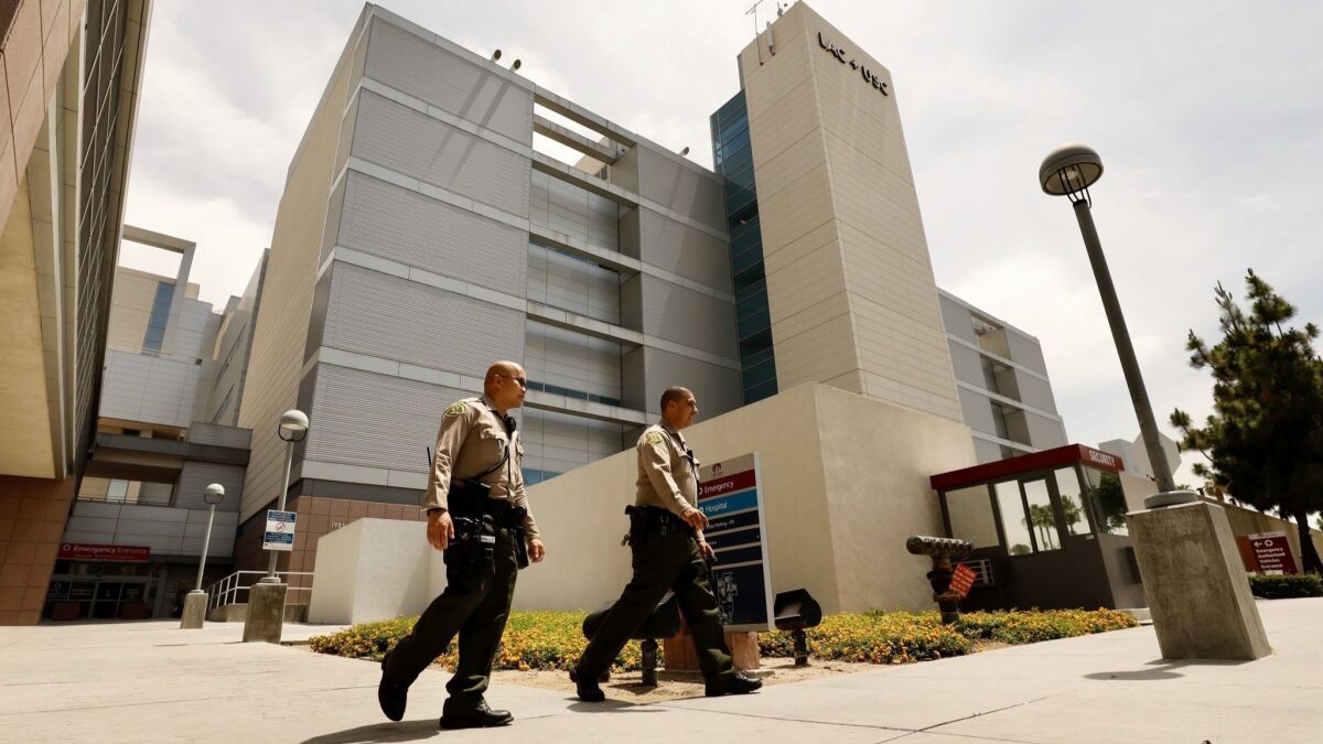 Los Angeles County sheriff's deputies outside L.A. County-USC Medical Center, where a deputy remains in “grave condition” after being shot in the head on Monday.