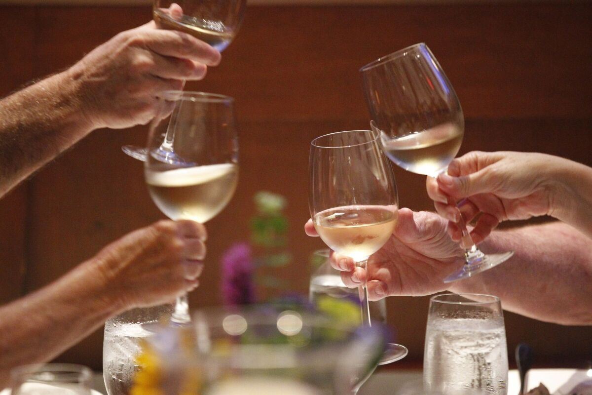 Guest hold out glasses of Carneros reserve chardonnay in a toast as they get ready to eat the second course.