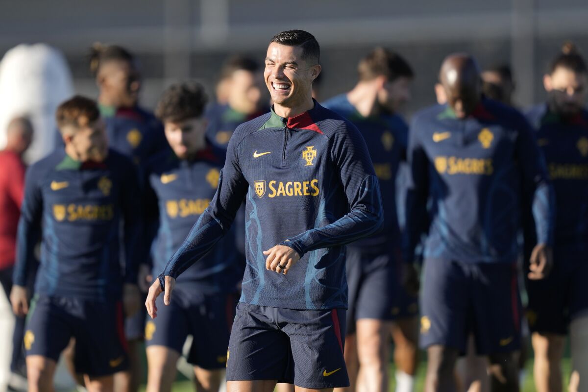 Portugal's Cristiano Ronaldo laughs as he arrives on the pitch for a Portugal soccer team training session in Oeiras, outside Lisbon, Tuesday, March 21, 2023. Portugal will play Liechtenstein Thursday in a Euro 2024 qualifying match in Lisbon, the first game under the new team head coach Roberto Martinez. (AP Photo/Armando Franca)