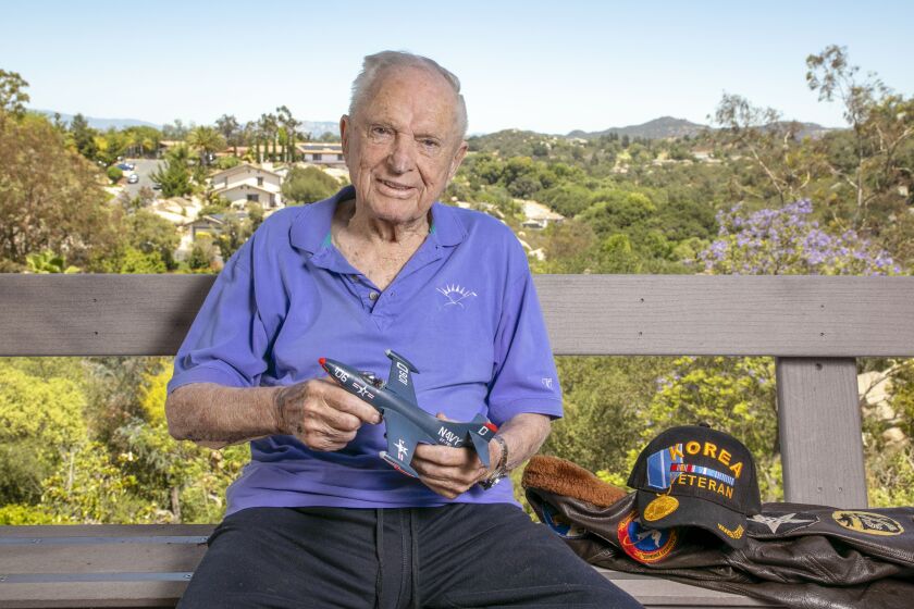 Escondido, CA - June 13: On a warm afternoon 97 year old war veteran Royce Williams sits on his rear patio deck overlooking a canyon in the Mountain Meadows area of Escondido. He's holding a model of the Navy F9F-5 Panther jet he flew in an aerial dogfight in the Korean War. (Charlie Neuman / For The San Diego Union-Tribune)