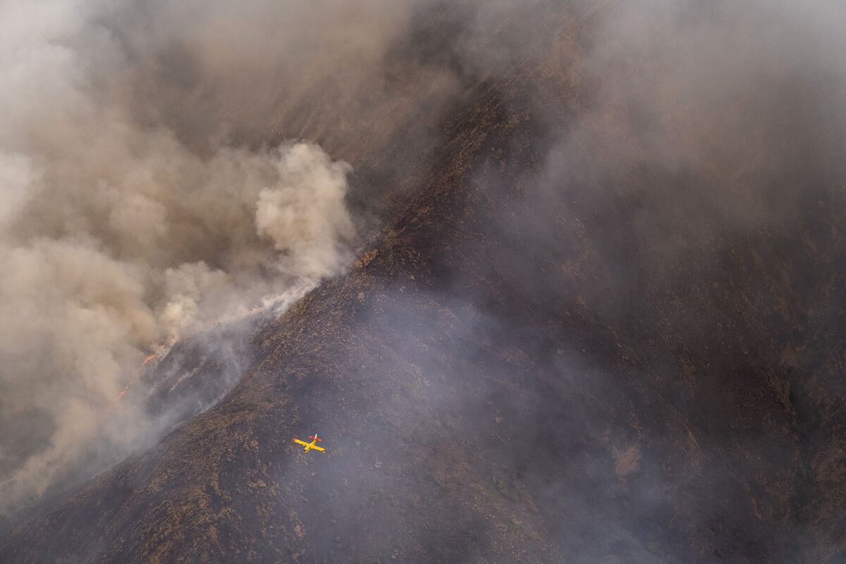 A seaplane flies over a wildfire near the town of Jubrique, in Malaga province, Spain, Monday, Sept. 13, 2021. Firefighting crews in southern Spain are looking at the sky for much-needed rainfall they hope can help extinguish a stubborn mega-fire that has ravaged 7,400 hectares (18,300 acres) in five days and displaced just under 3,000 people from their homes. Authorities are describing the blaze in Sierra Bermeja, a mountain range in the Malaga province, as a sixth-generation fire of the extreme kind brought by the shifting climate on the planet. (AP Photo/Pedro Armestre)