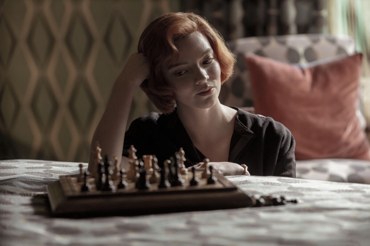 Anya Taylor-Joy as Beth Harmon looks at a chess board in "The Queen's Gambit."