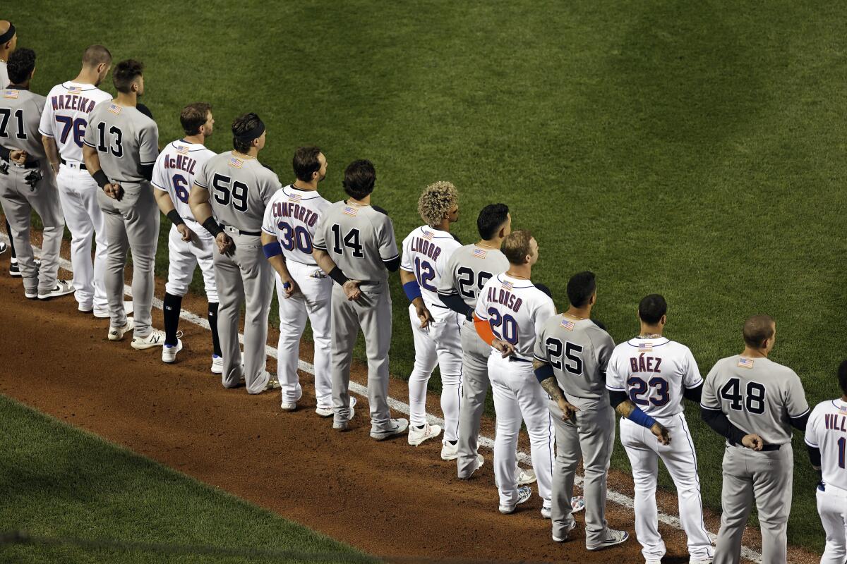 The New York Yankees and the New York Mets line up together along the baselines for the 20th anniversary of the 9/11 terrorist attacks before a baseball game on Saturday, Sept. 11, 2021, in New York. (AP Photo/Adam Hunger)