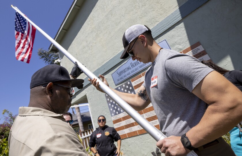 Marine Cpl. Xavier Cardona and Don Gibson raise a new American flag and flagpole.