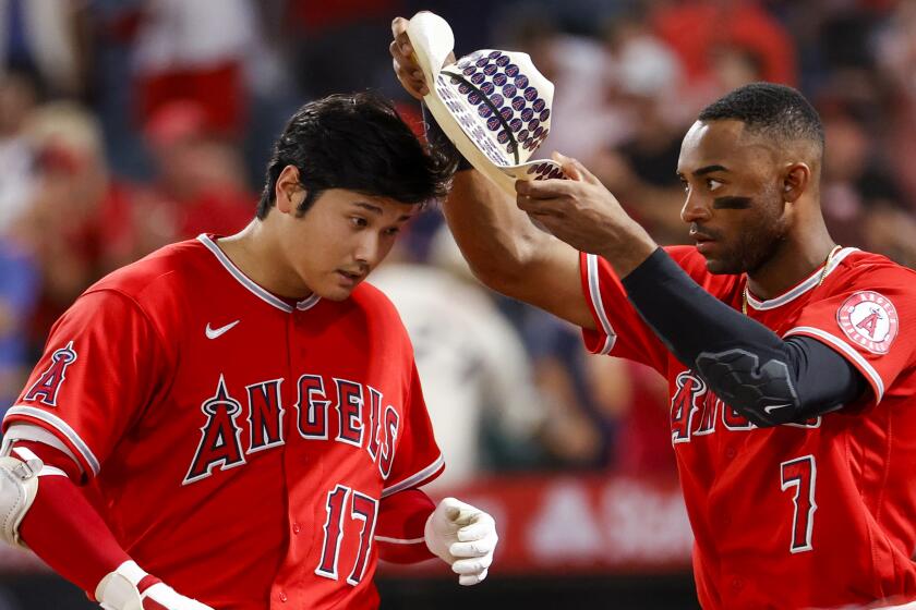 Los Angeles Angels' Jo Adell (7) puts a cowboy hat onto Shohei Ohtani (17) while celebrating.