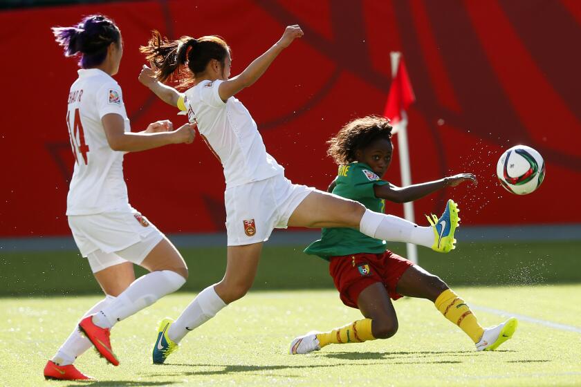 Wu Haiyan and Zhao Rong of China try to block a shot from Gabrielle Onguene of Cameroon during a Round of 16 match at the Women's World Cup.