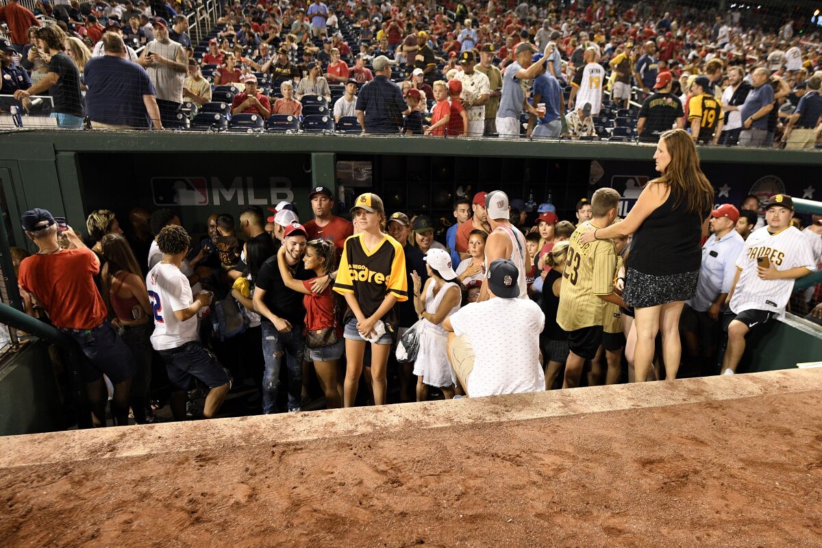 People stand in the visitors' dugout after play was stopped during the Padres-Nationals game 