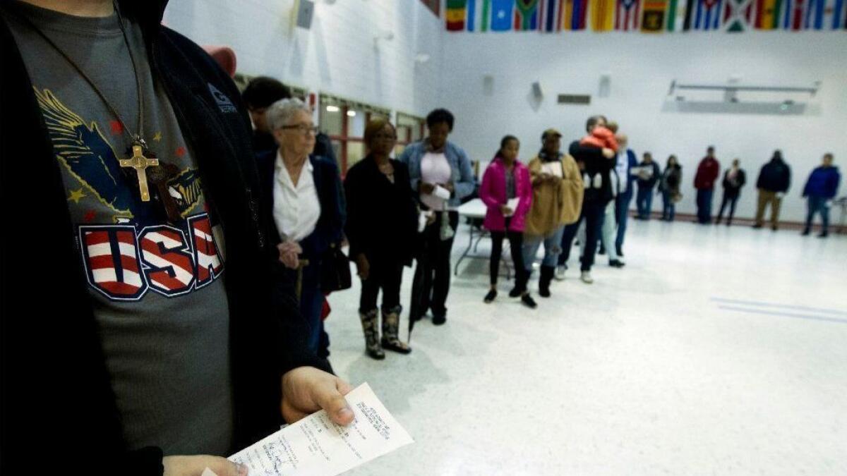 People wait in line Tuesday at a polling place in Silver Spring, Md.