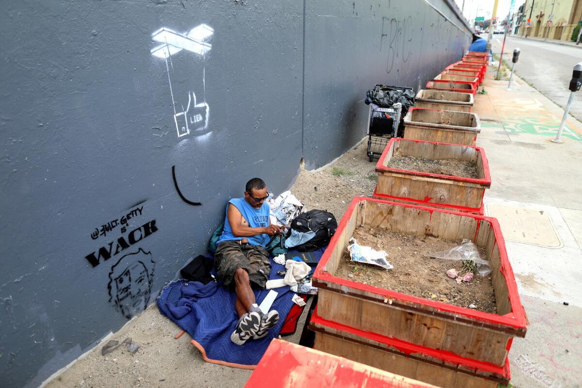 A homeless man found a place to set up camp where planters were placed to discourage people from camping along West 18th Street in Los Angeles.