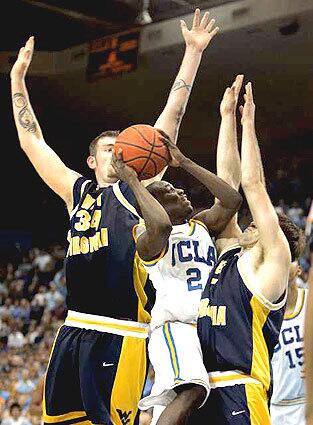 UCLA's Darren Collison drives to the basket but has his shot blocked by West Virginia's Kevin Pittsnogle, left, and Johannes Herber.