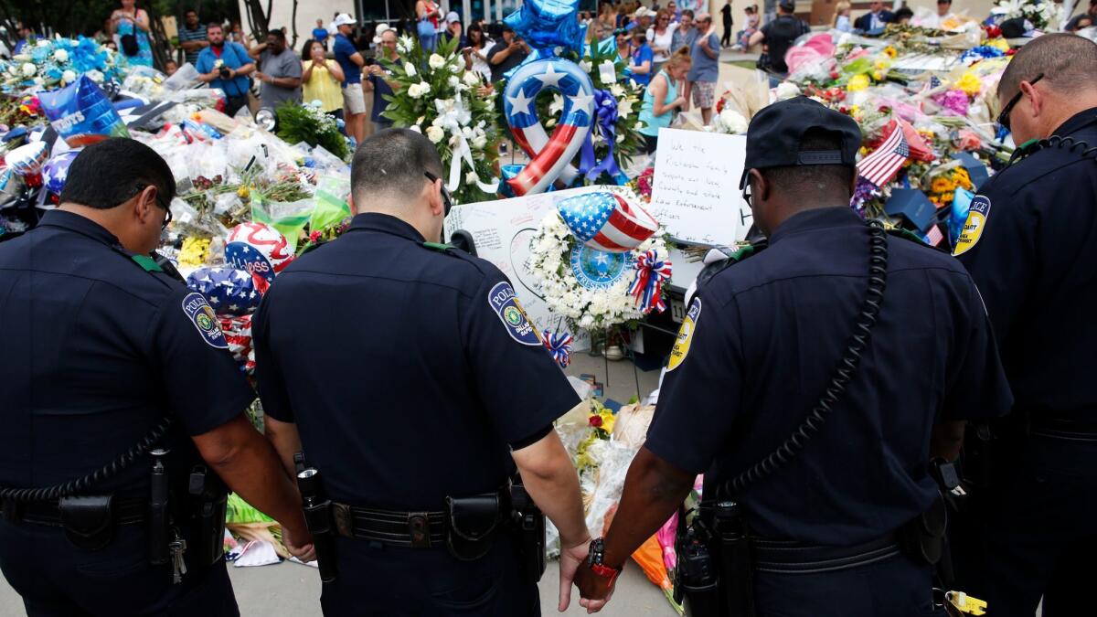 Officers pray in front of the Dallas police headquarters in July 2016 after a sniper attack that left five law enforcement officers dead.