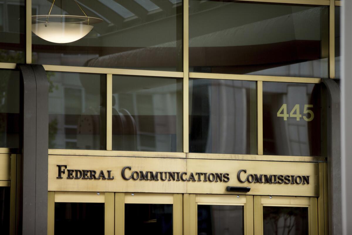 A glass building with brass doors and a sign that says Federal Communications Commission 