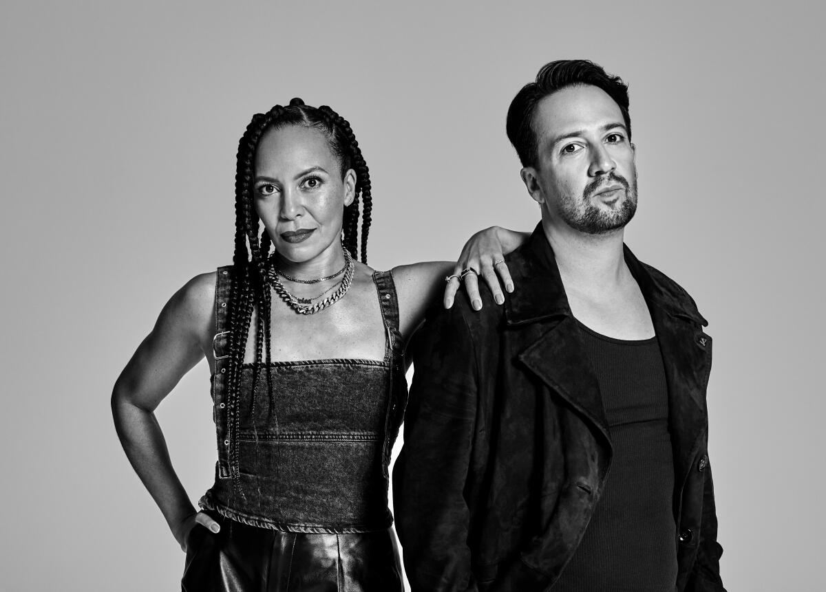 A black-and-white photo of Eisa Davis with her arm on Lin-Manuel Miranda's shoulder.
