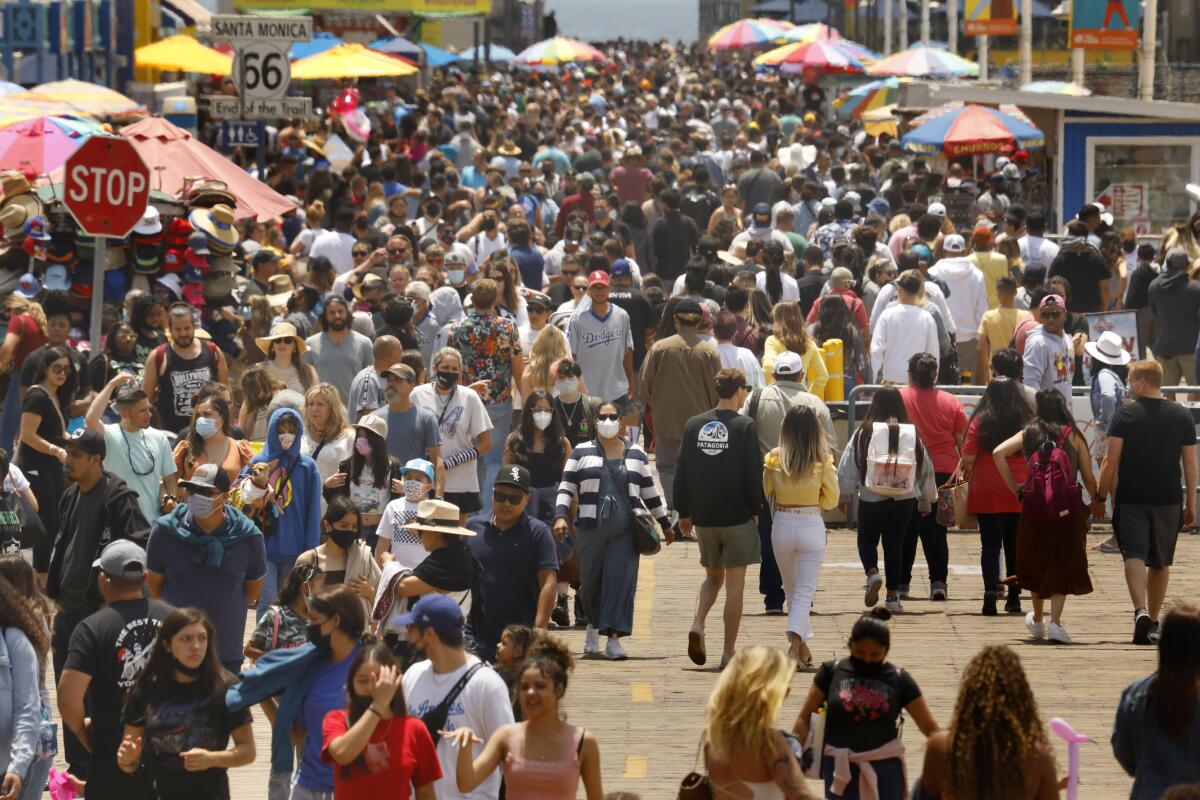 Some wearing masks, others not, people crowd the Santa Monica Pier on Memorial Day.