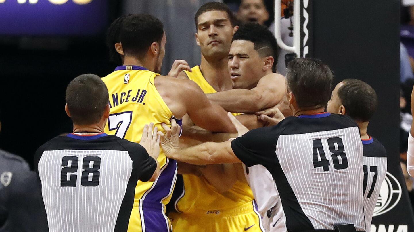 Suns guard Devin Booker, right, and Lakers forward Larry Nance Jr. (7) scuffle as the referees and Lakers center Brook Lopez try to intervene during the second half.