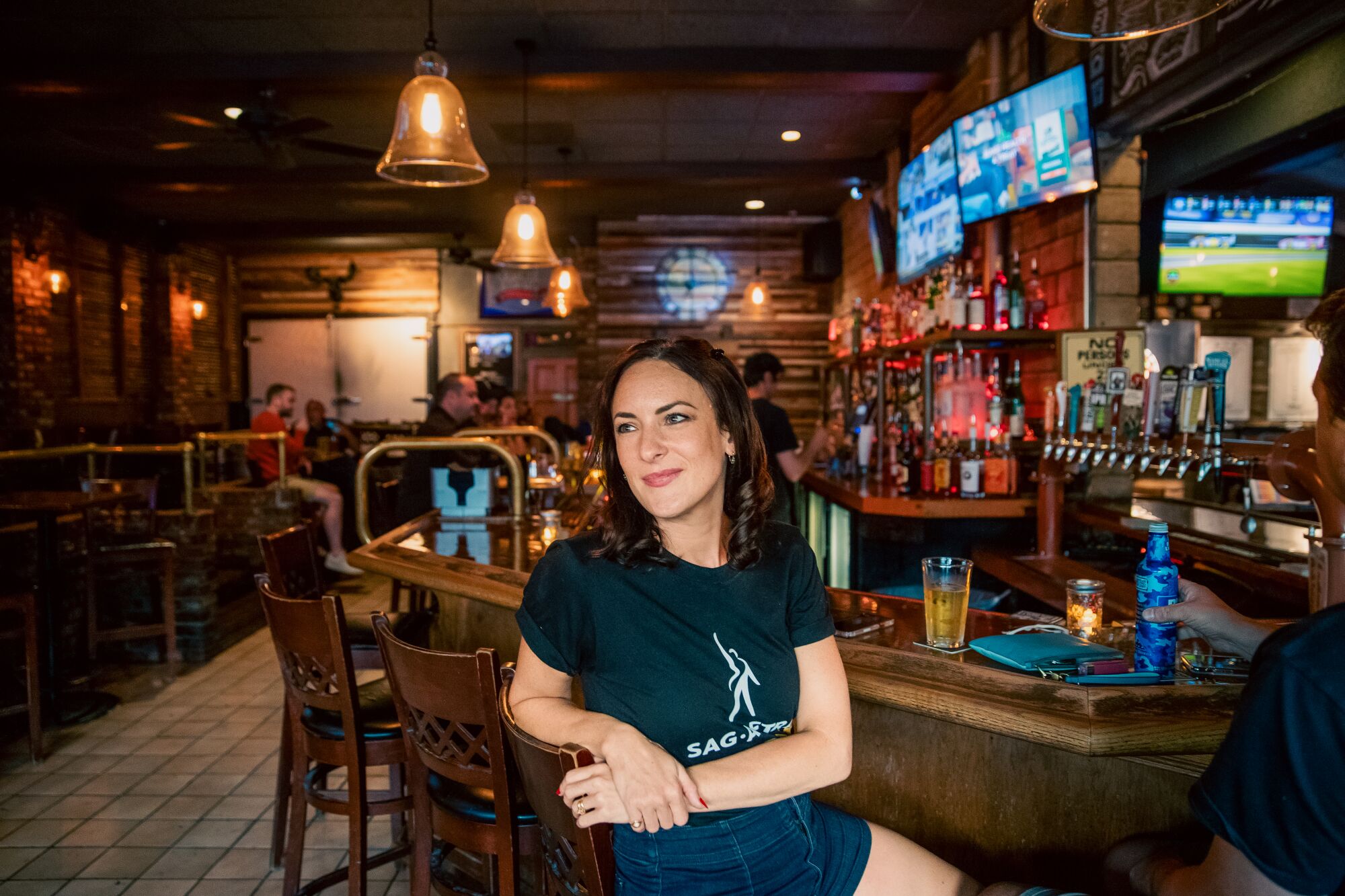 A woman sits in a bar setting.